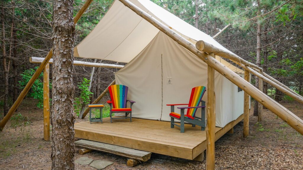 Glamping canvas walled tent with rainbow Adirondack chairs on the deck