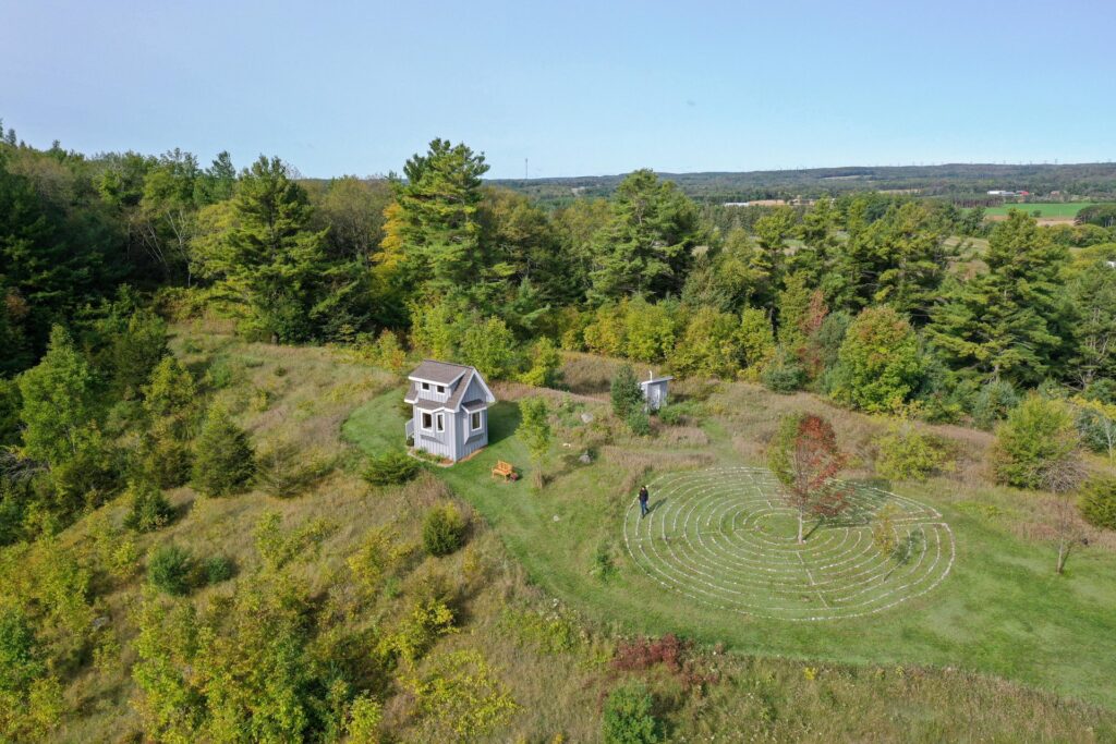 Drone view of a tiny cabin and a labyrinth in fall