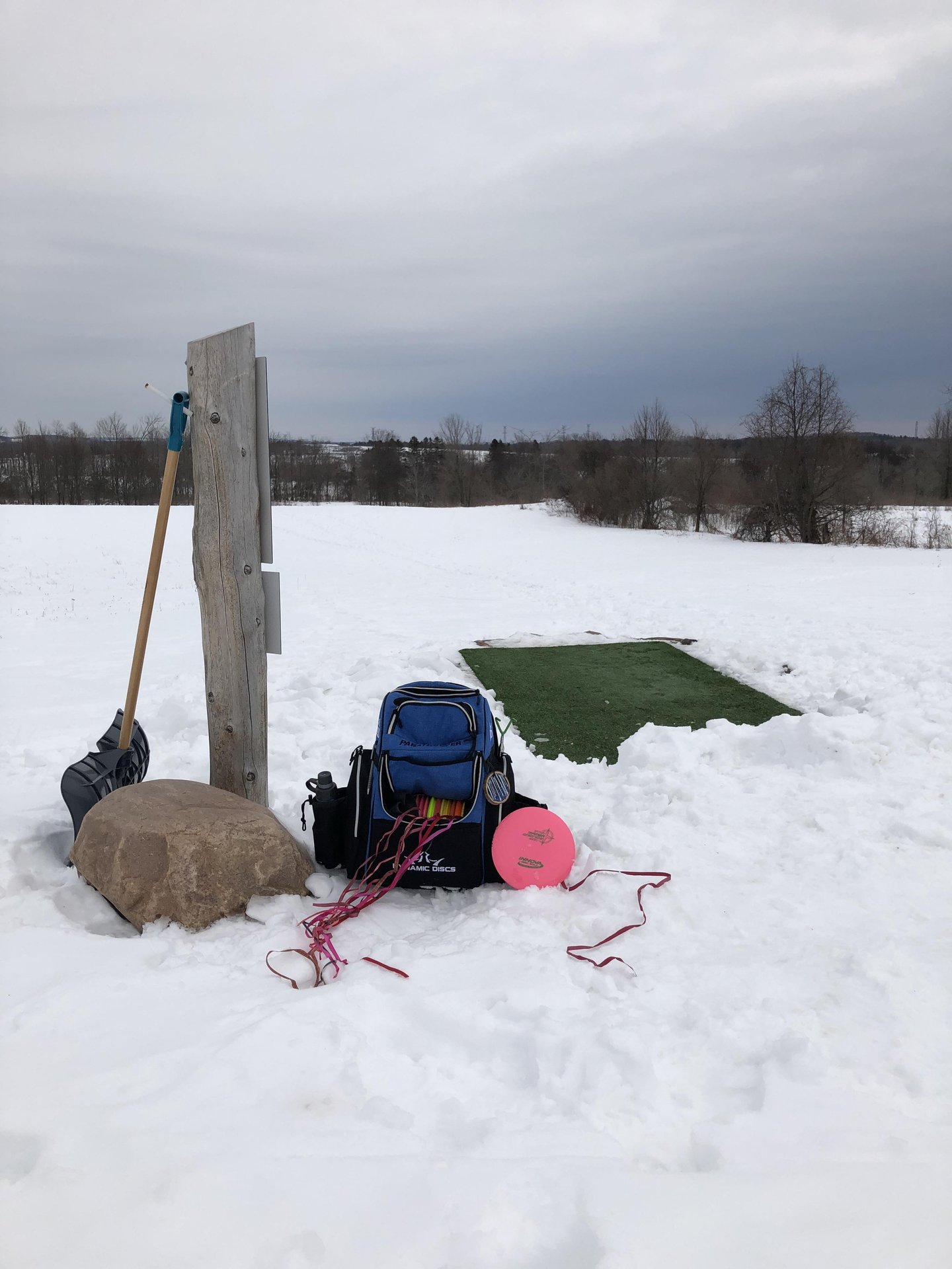 backpack and discs at a tee on a disc golf course in winter
