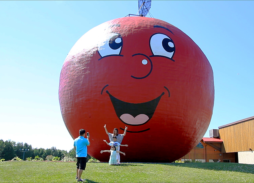 People taking a photograph in front of The Big Apple