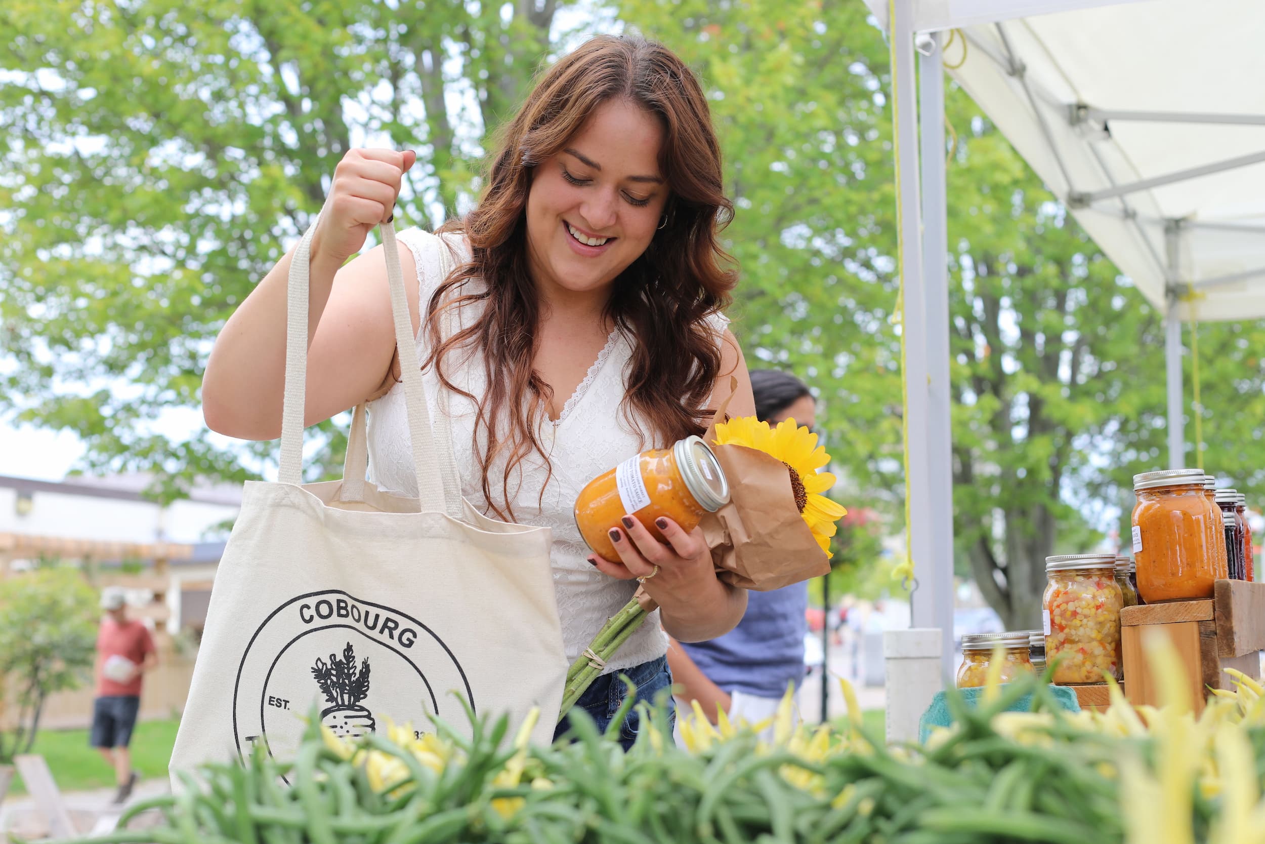 Woman putting a jar of preserves into a Cobourg Farmers Market shopping tote