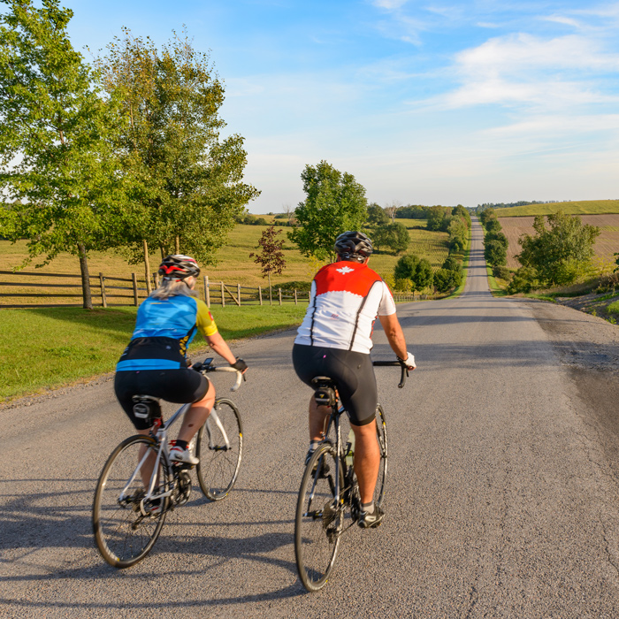 two people riding bikes down a country road