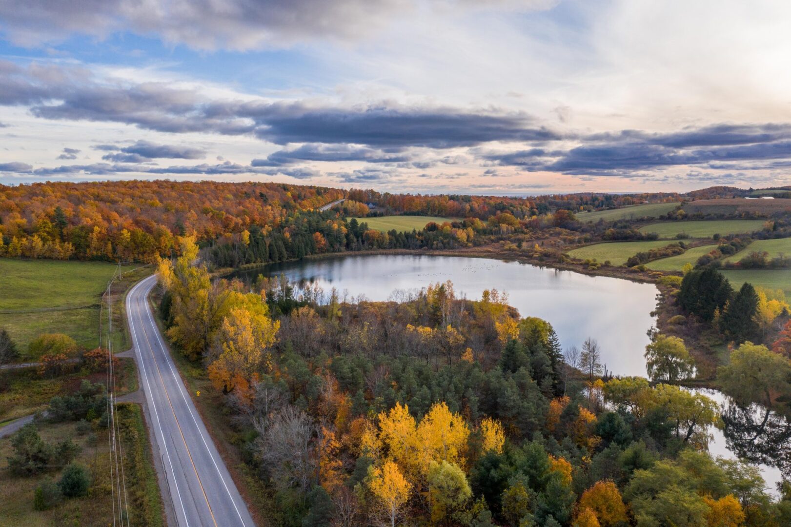 Drone view of a highway running alongside a body of water in fall