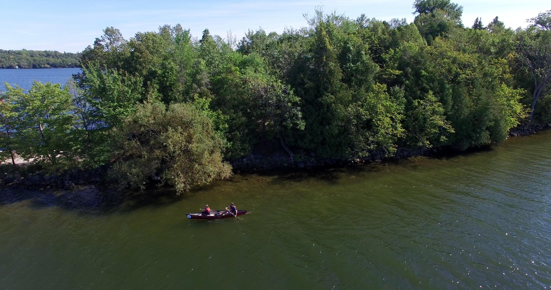 Drone view of people in a canoe paddling past an island on Rice Lake