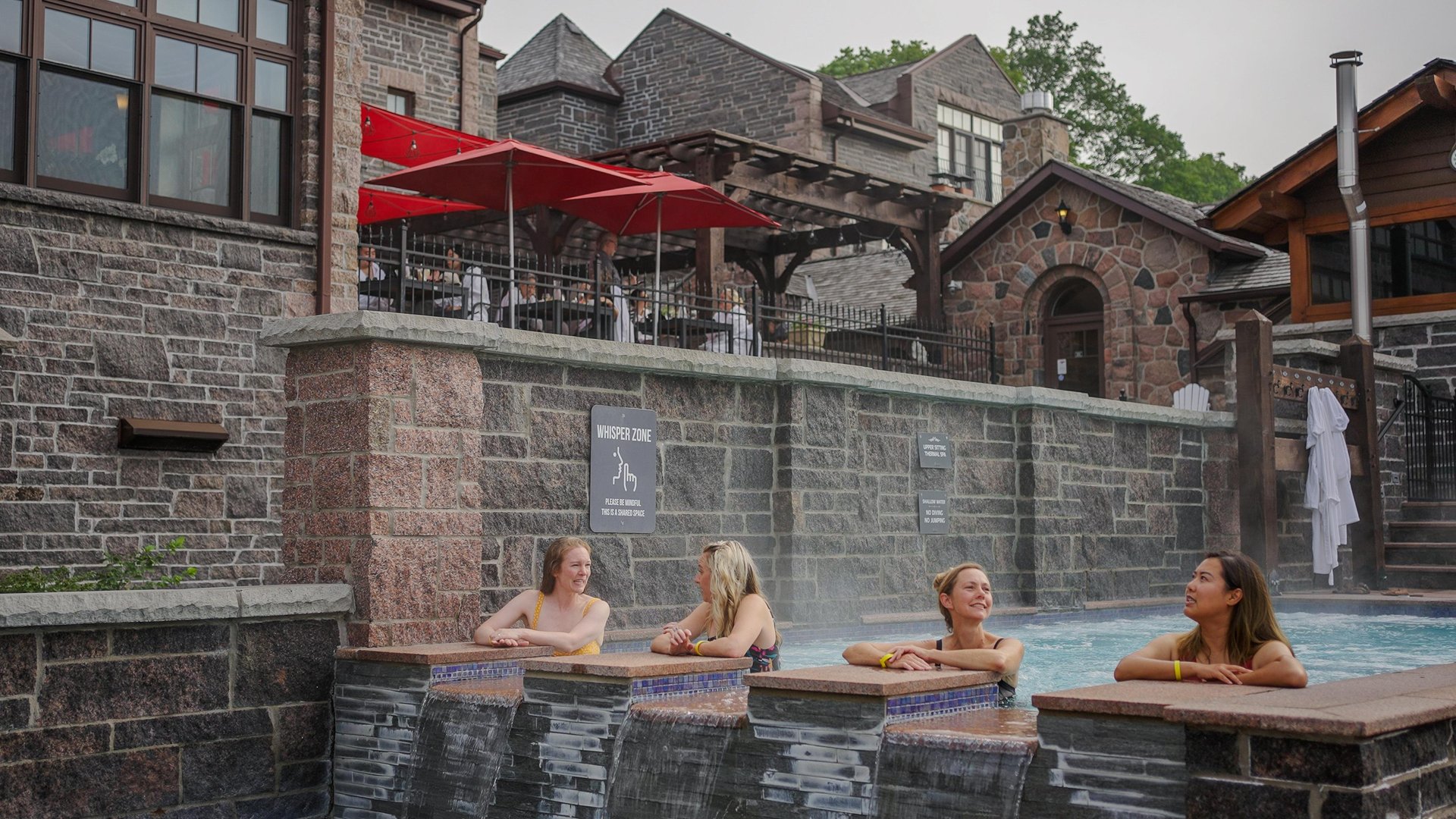 4 women enjoying a hydrotherapy pool at Ste Anne's spa with stone walls in the background.