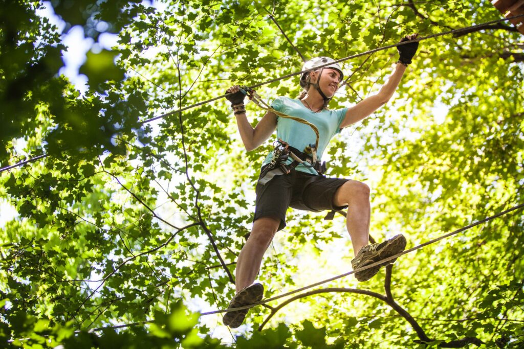 Person walking on a high rope through the trees in summer.