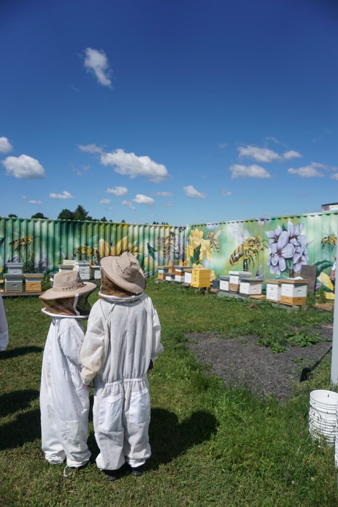 Two people in bee suits looking at a wall mural