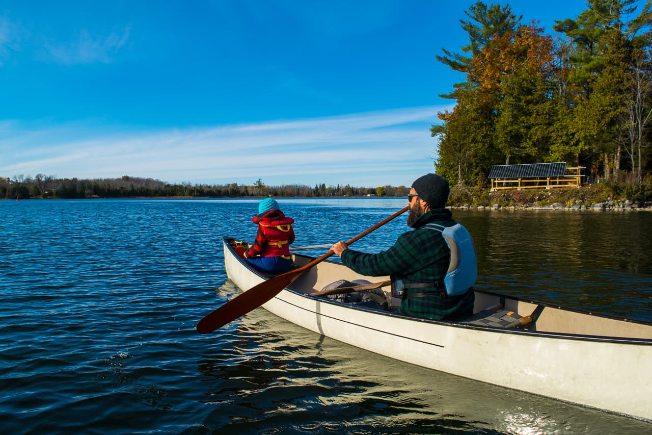 Father and child paddling in a canoe in fall