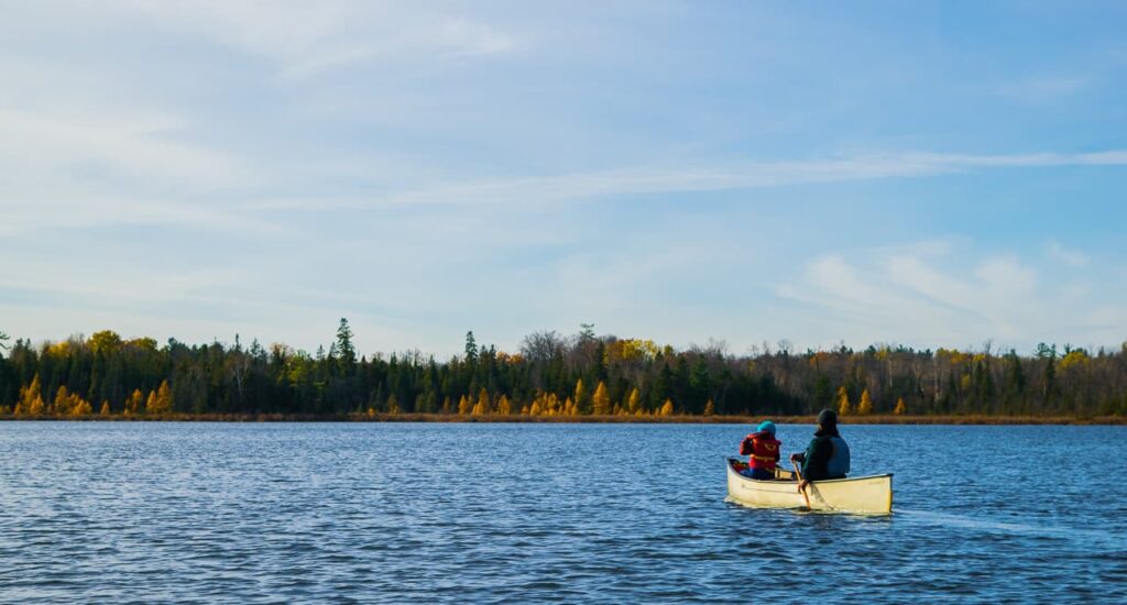 2 people on the lake in a white canoe in fall
