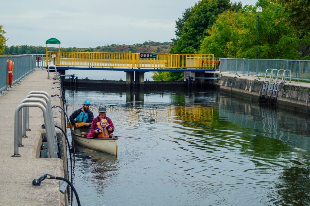 Couple in a white canoe at a set of locks on the Trent Severn Waterway.