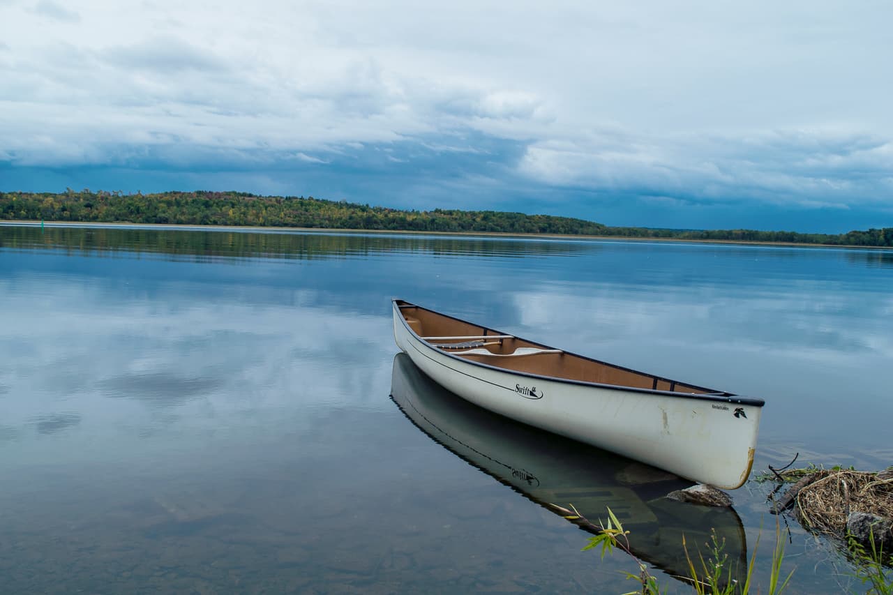 White canoe at the shore on a small lake in the fall