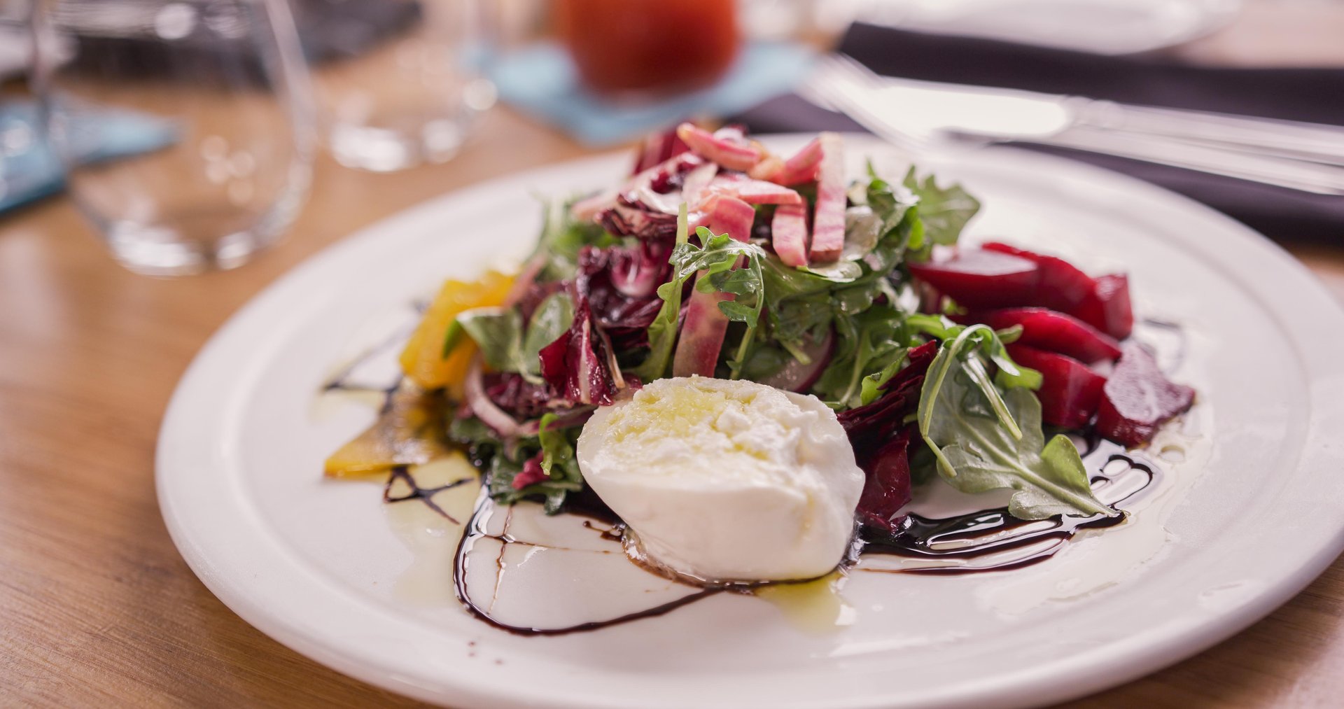 A salad with fresh mozzarella cheese on a white plate