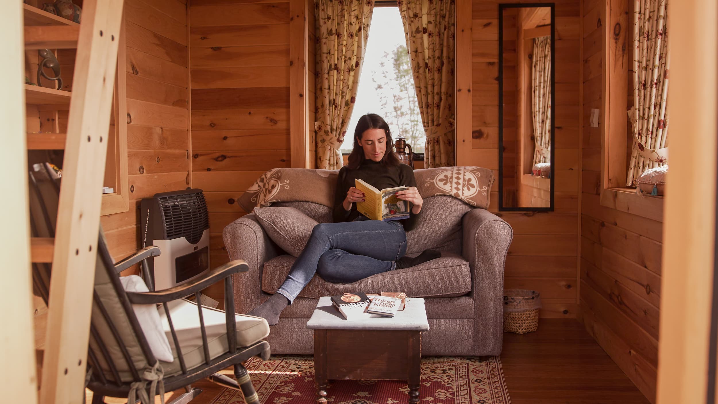 Woman sitting in a tiny cabin reading a book