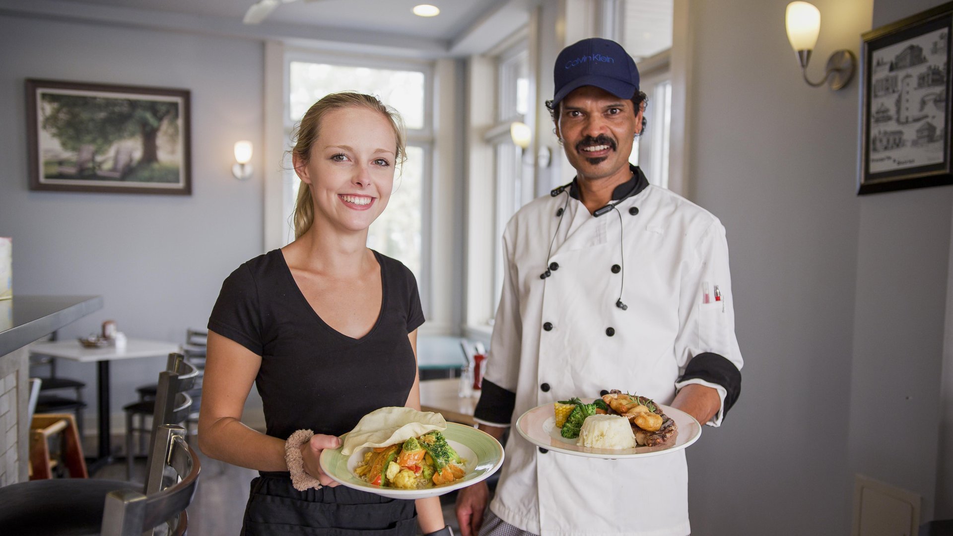 Server and chef presenting food at a restaurant
