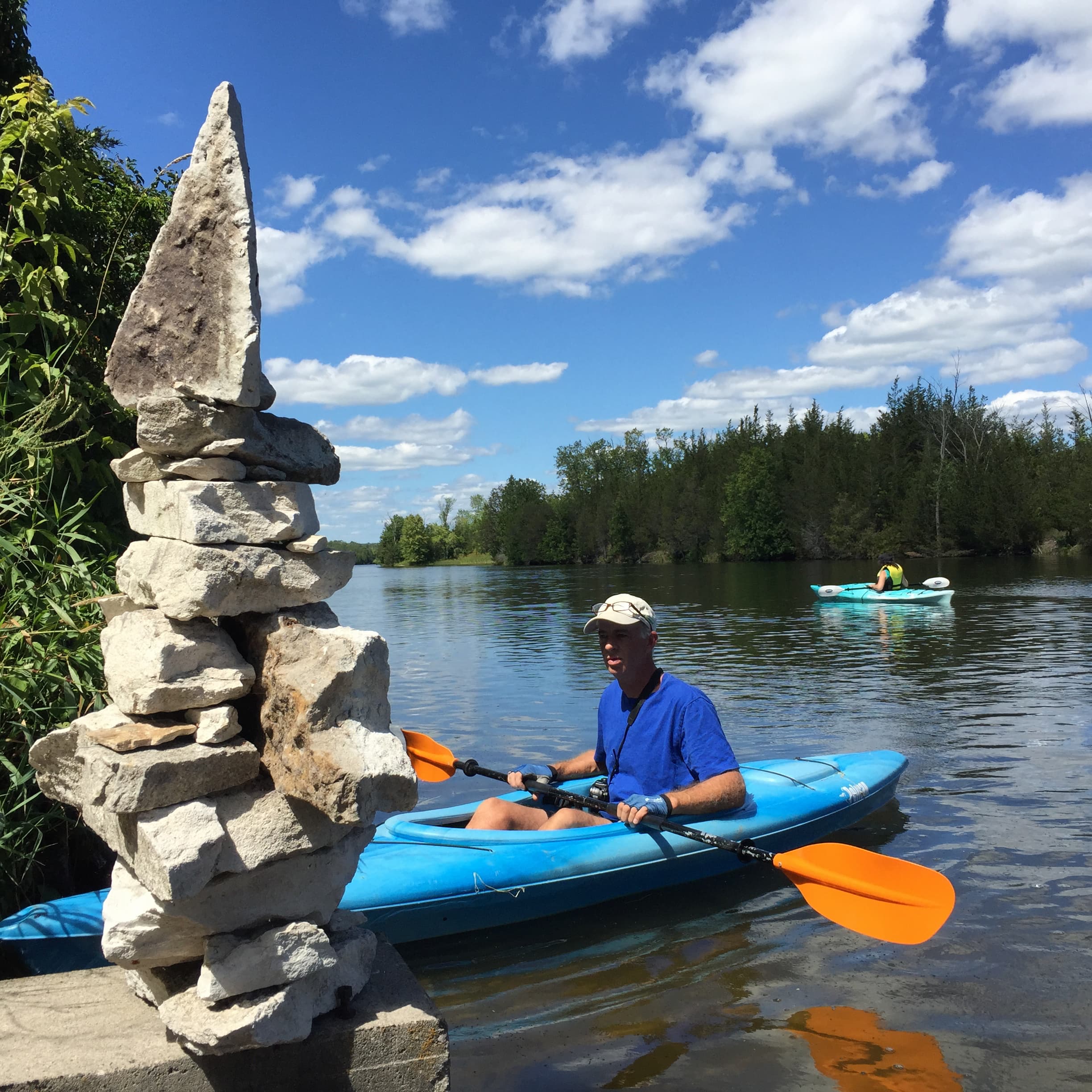 Man kayaking and stopping to look at a stone sculpture