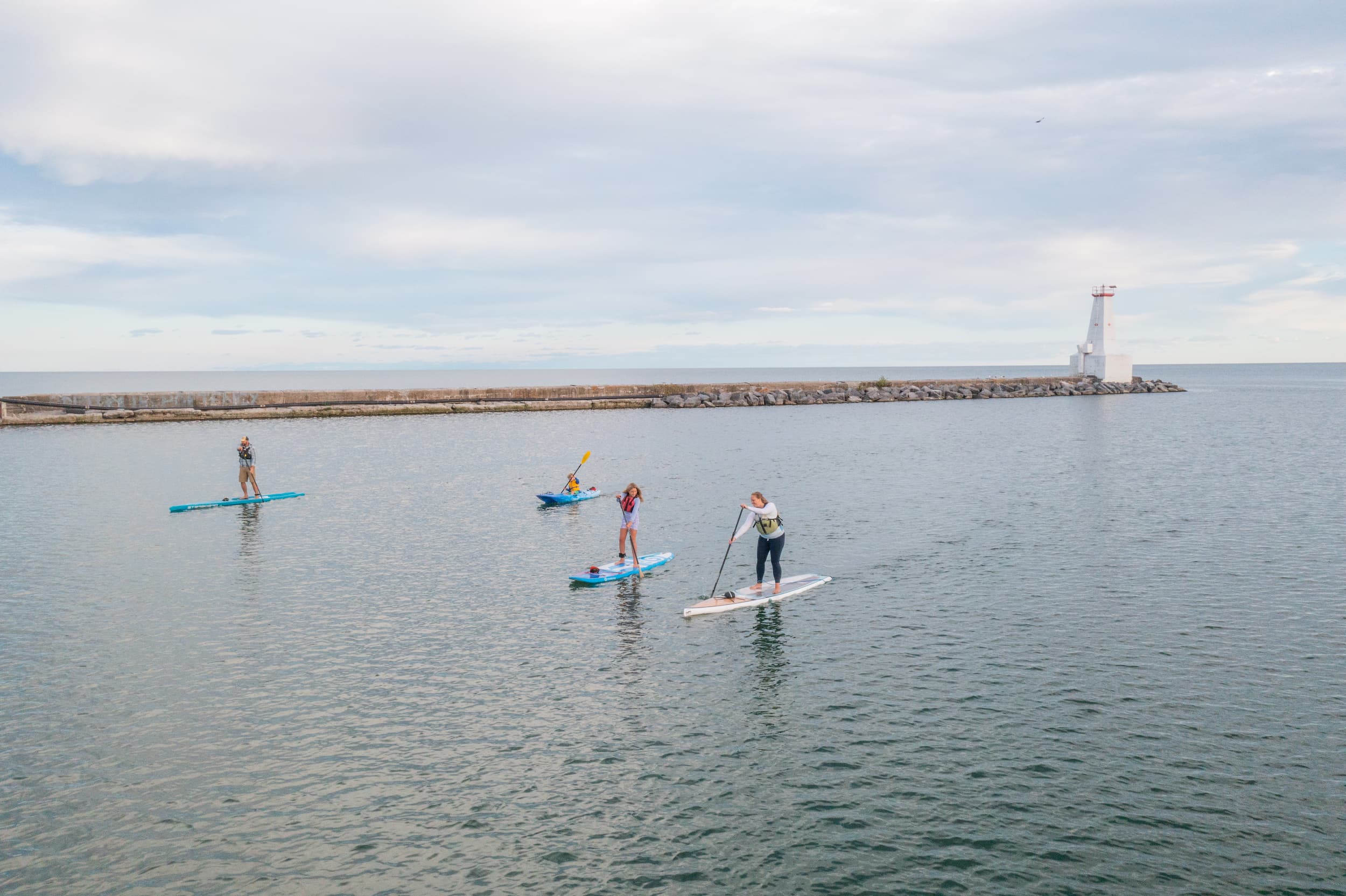 Drone view of family on paddle boards and a kayak in Cobourg harbour.
