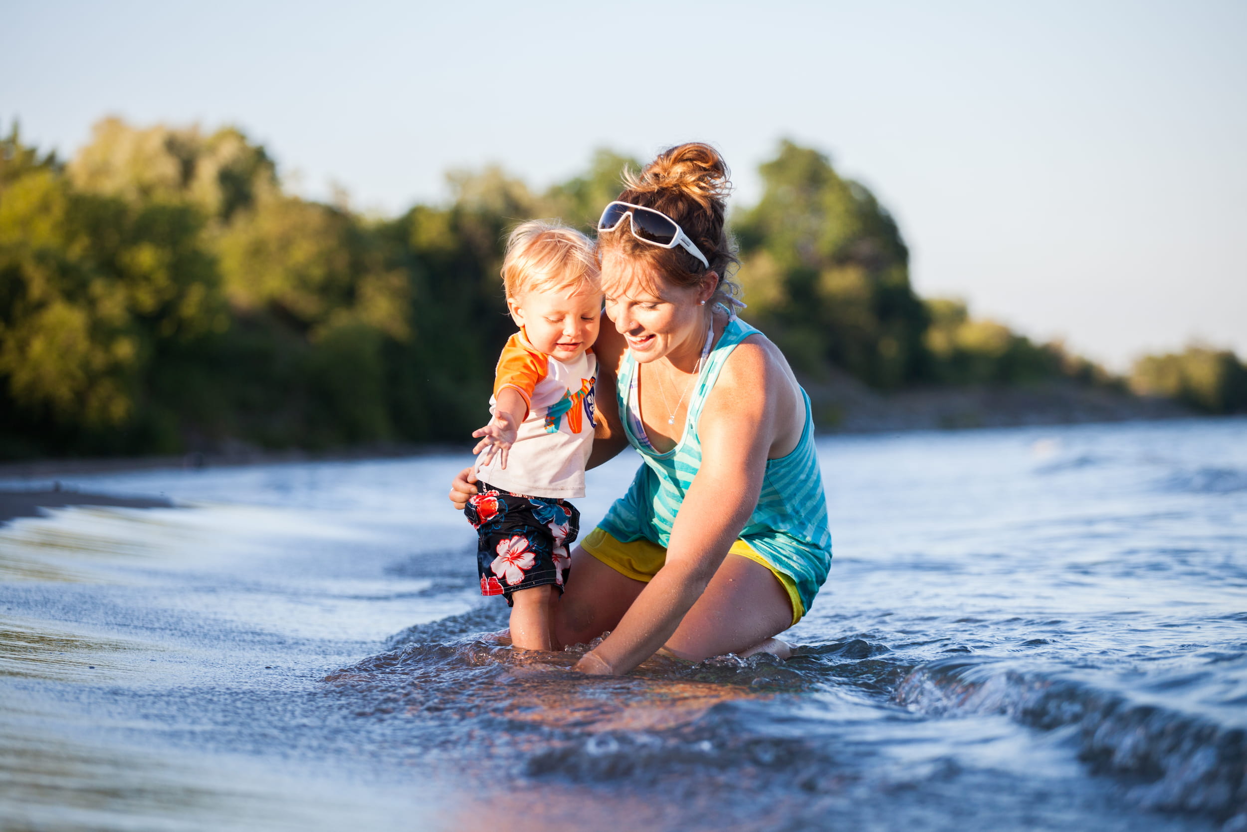 Woman holding her child while they play in the water at the shore of Port Hope Beach.