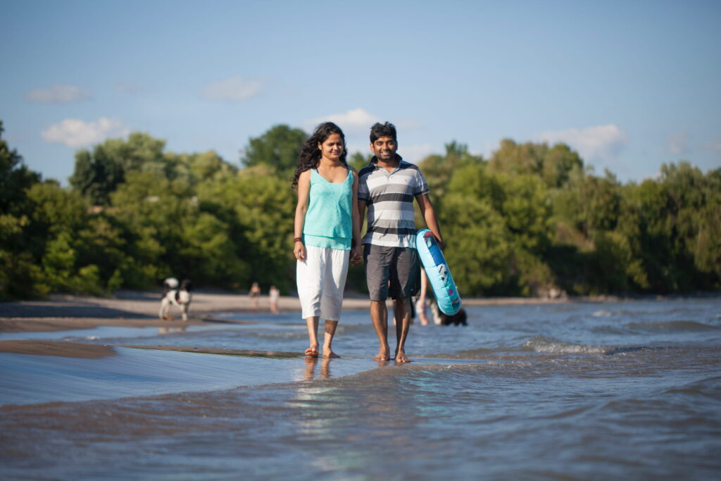 Couple walking the beach in Port Hope. Man carrying an inflatable tube.