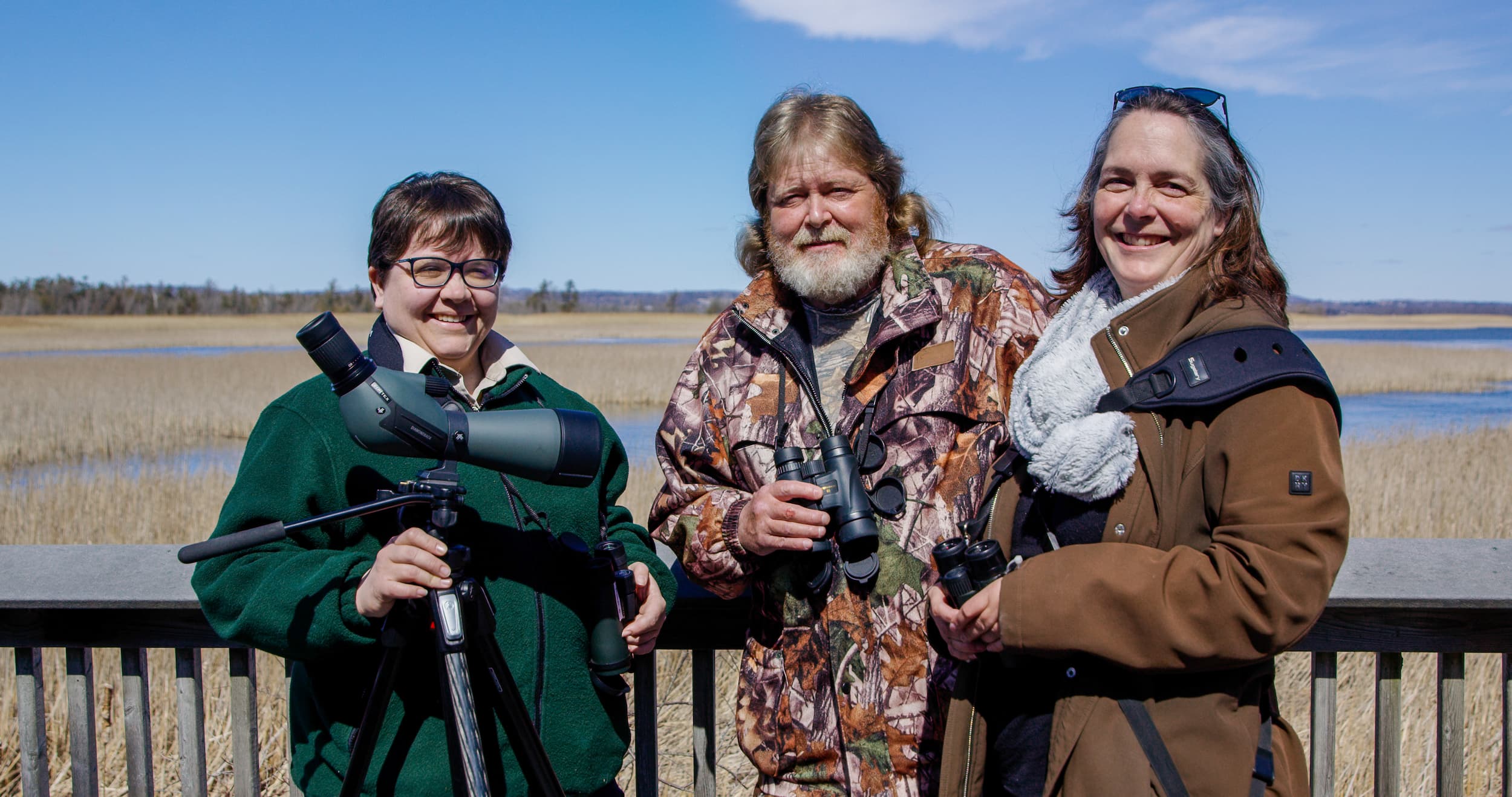 Group of three birdwatchers smiling at the camera