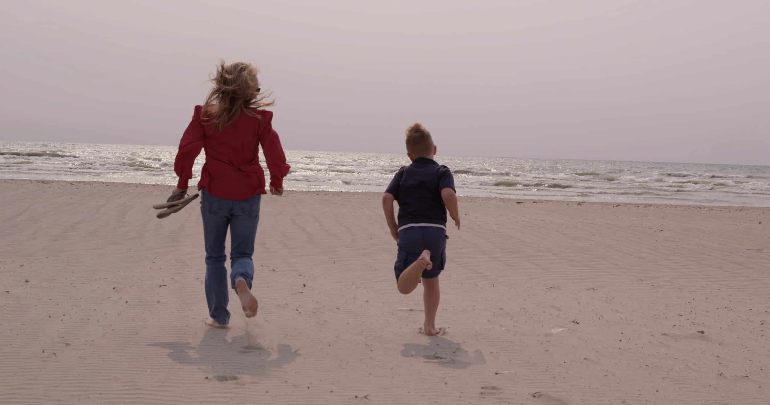 Mother and son running towards the water at Presqu'ile Provincial Park.
