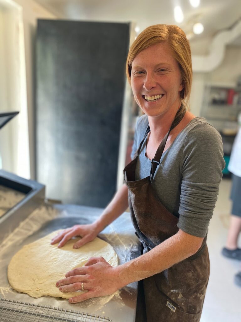 Woman smiling at camera while making pizza