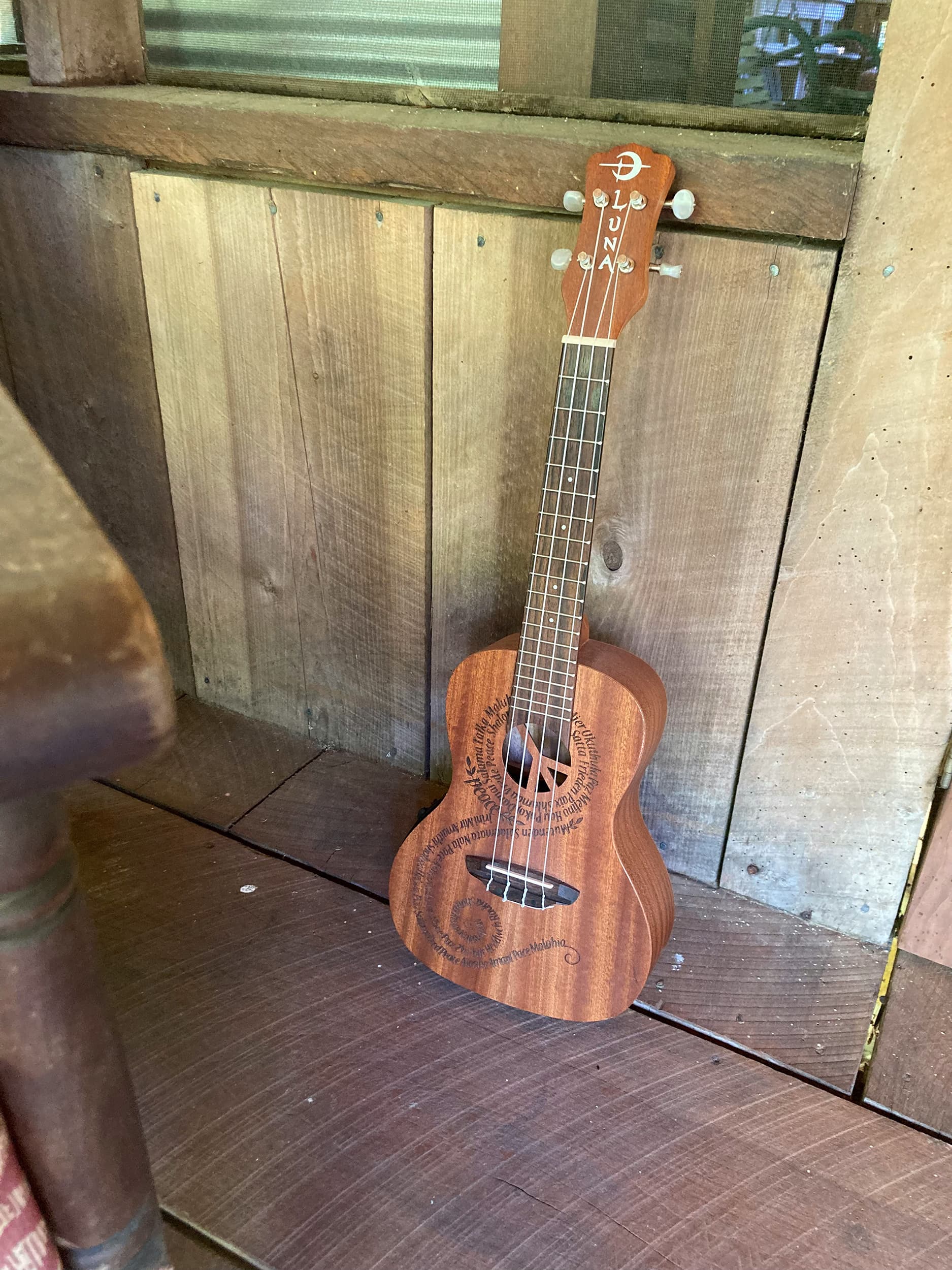 Ukulele leaning against a wooden wall on a porch.