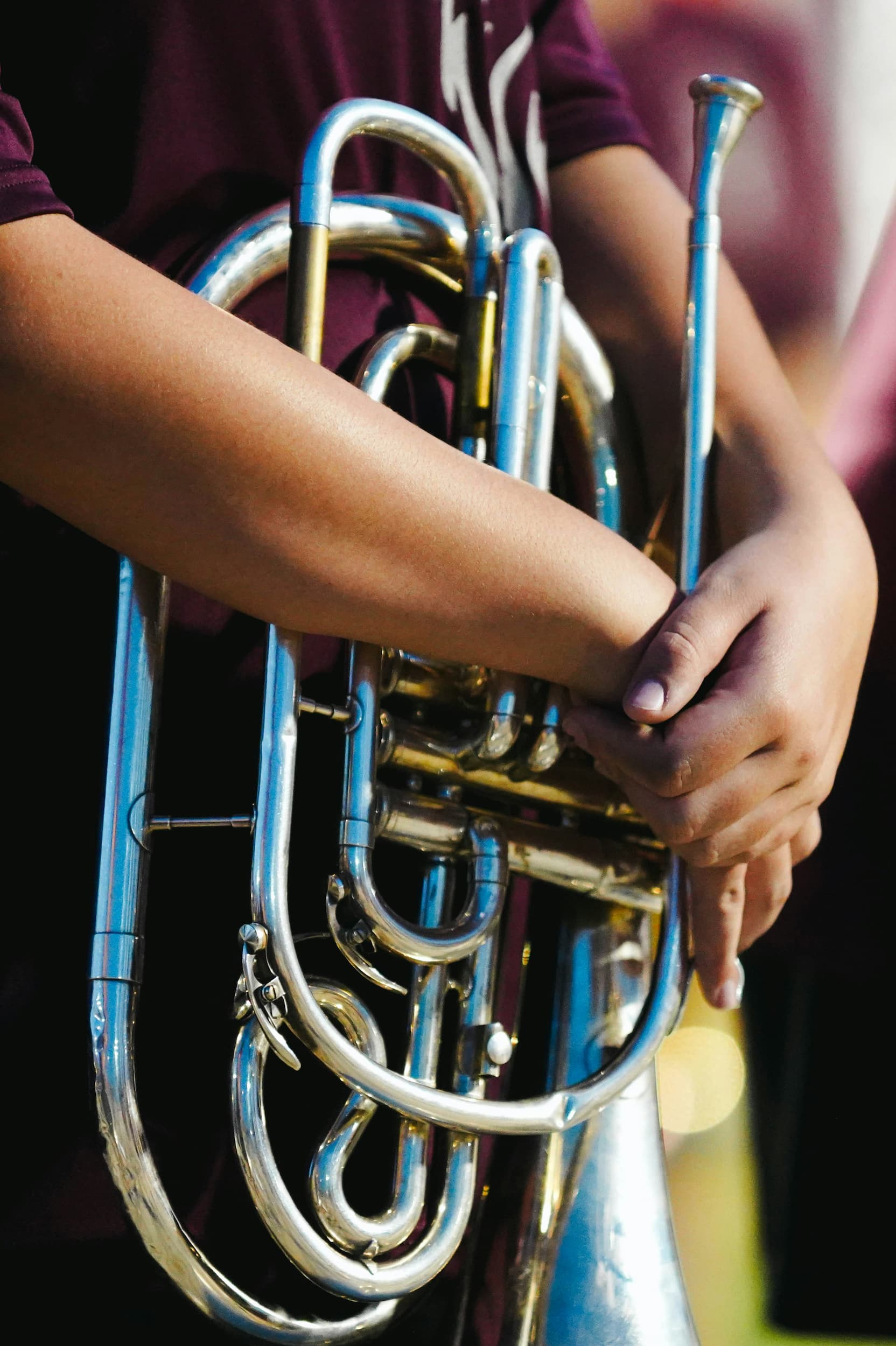 Arms wrapped around a baritone brass instrument.
