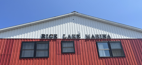 Red barn shaped building with a white peak and black writing.