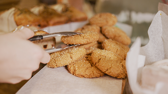 a pair of tongs picking up a cookie off a pile.