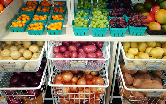 Baskets of potatoes, onions, sweet potatoes, grapes, mangoes and cherry tomatoes