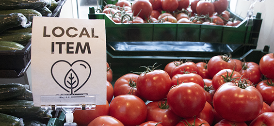 Basket of tomatoes with a local items sign.