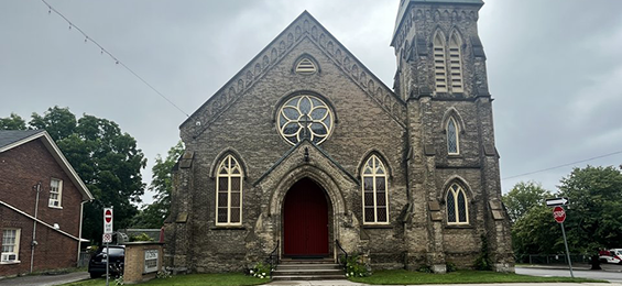 Large dark grey stone building with white trim.