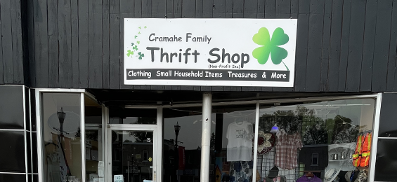 Black building with large front windows and a white & green sign.