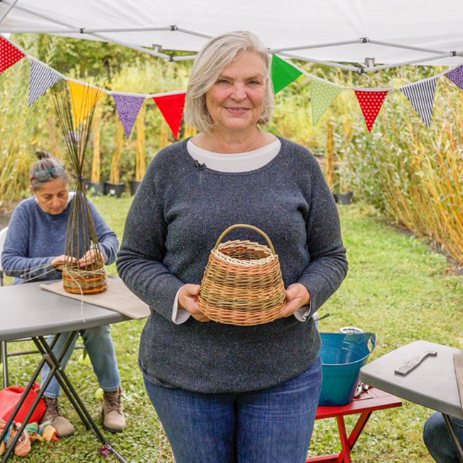 Woman holding a brown wicker basket.