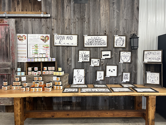 Black and white signs on a wood table and wall beside a candle display.