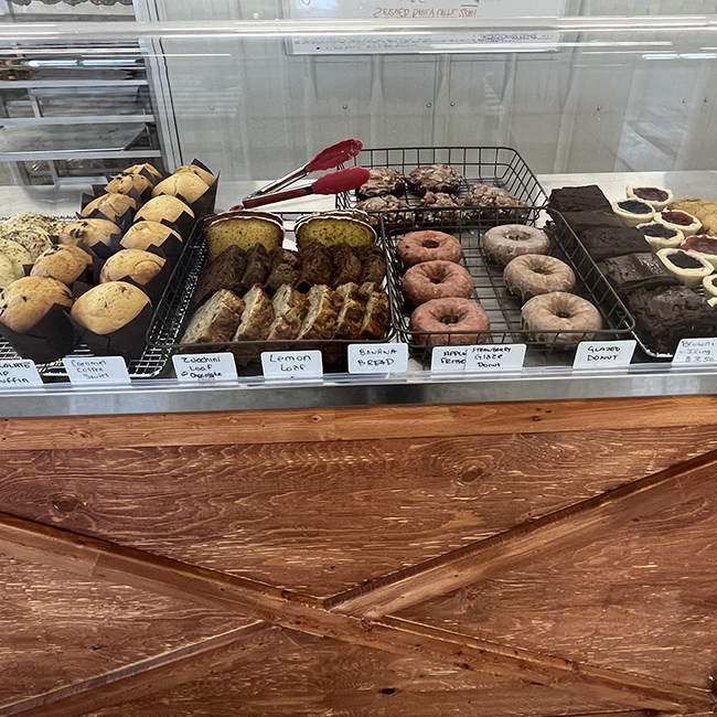 Multiple baked goods on trays behind glass.