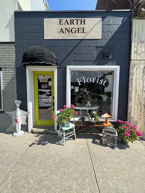 Dark grey building with green accents and items in front of window.