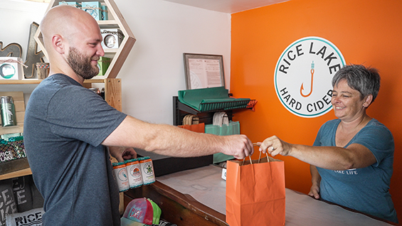 Man and woman passing an orange bag over a counter.