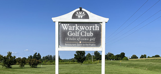 Black sign with white writing and framing.