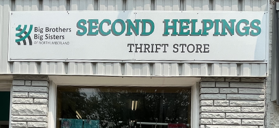 White sign with green and black writing on a building.