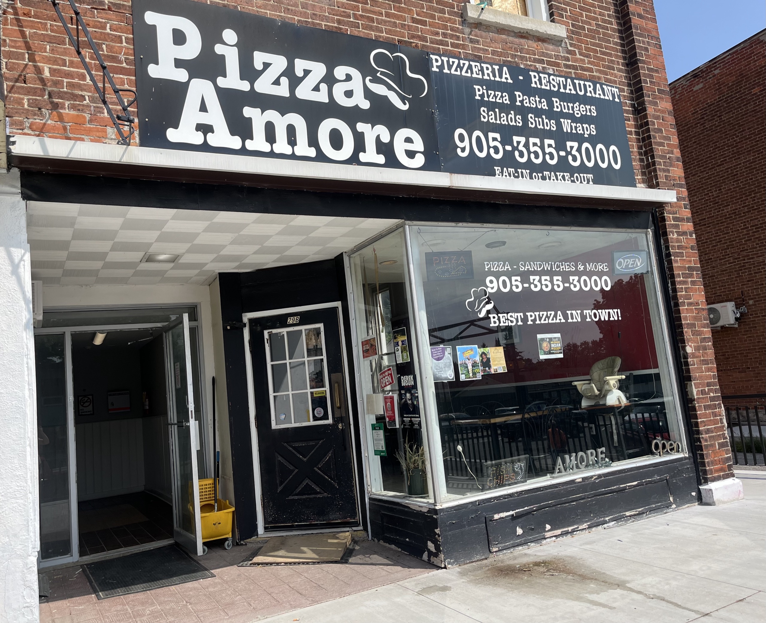 Photo of the Pizza Amore store front. Sign above the store reads "Pizza Amore. Pizzeria. Restaurant. 905-355-3000."