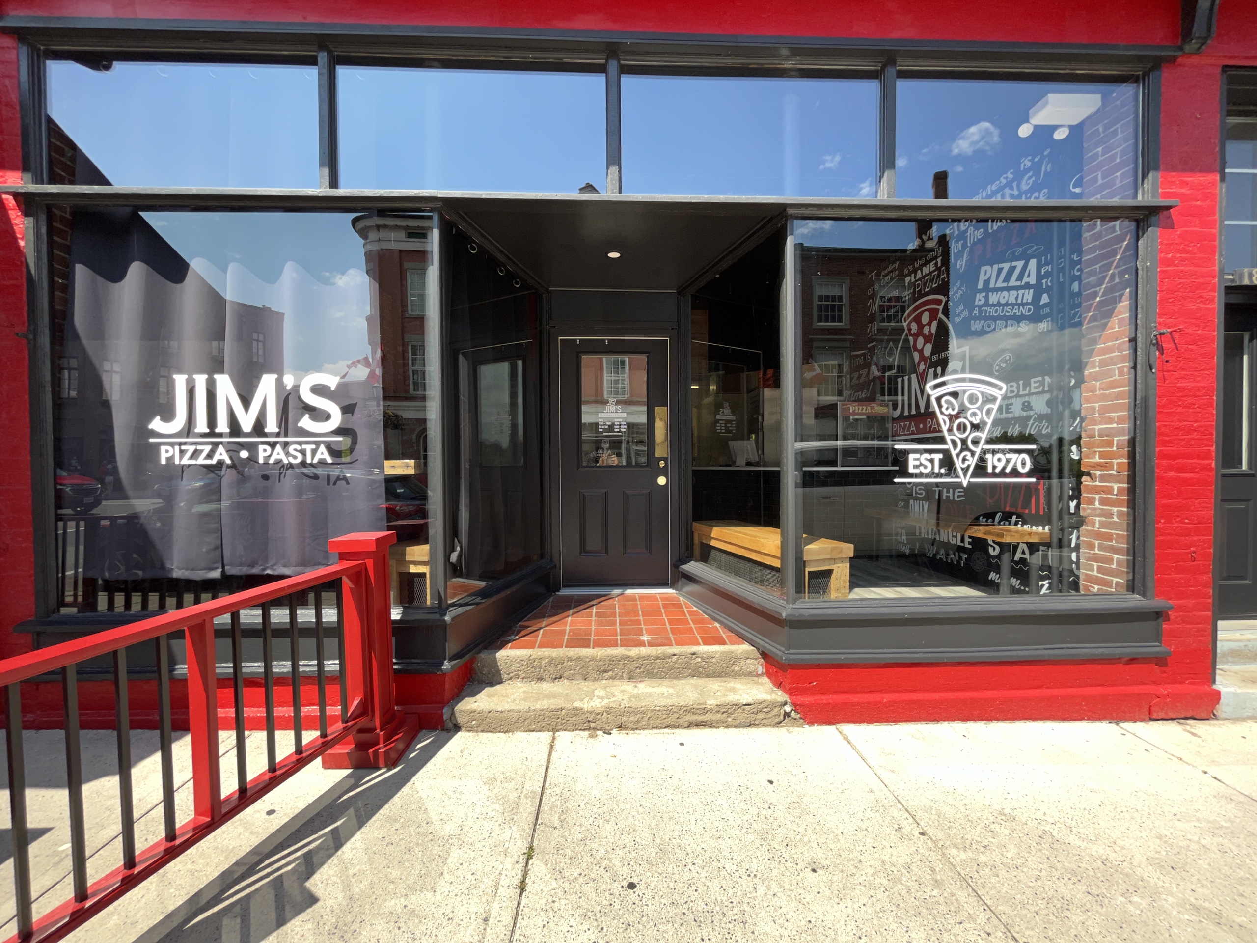 Photo of Jim's Pizza and Pasta storefront. Writing on the glass reads "Jim's Pizza and Pasta. Est. 1970."
