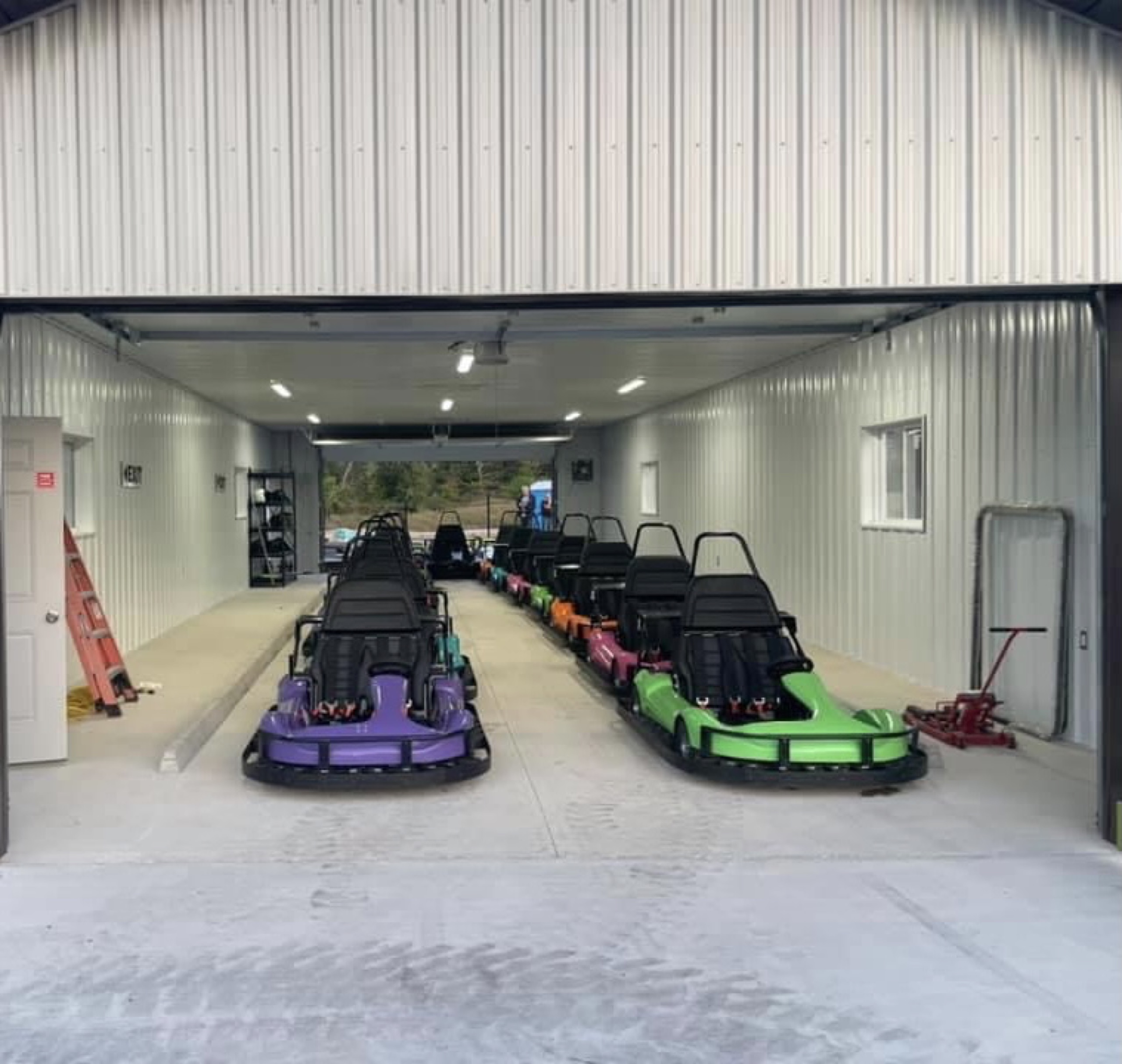 go karts lined in 2 rows in a garage.