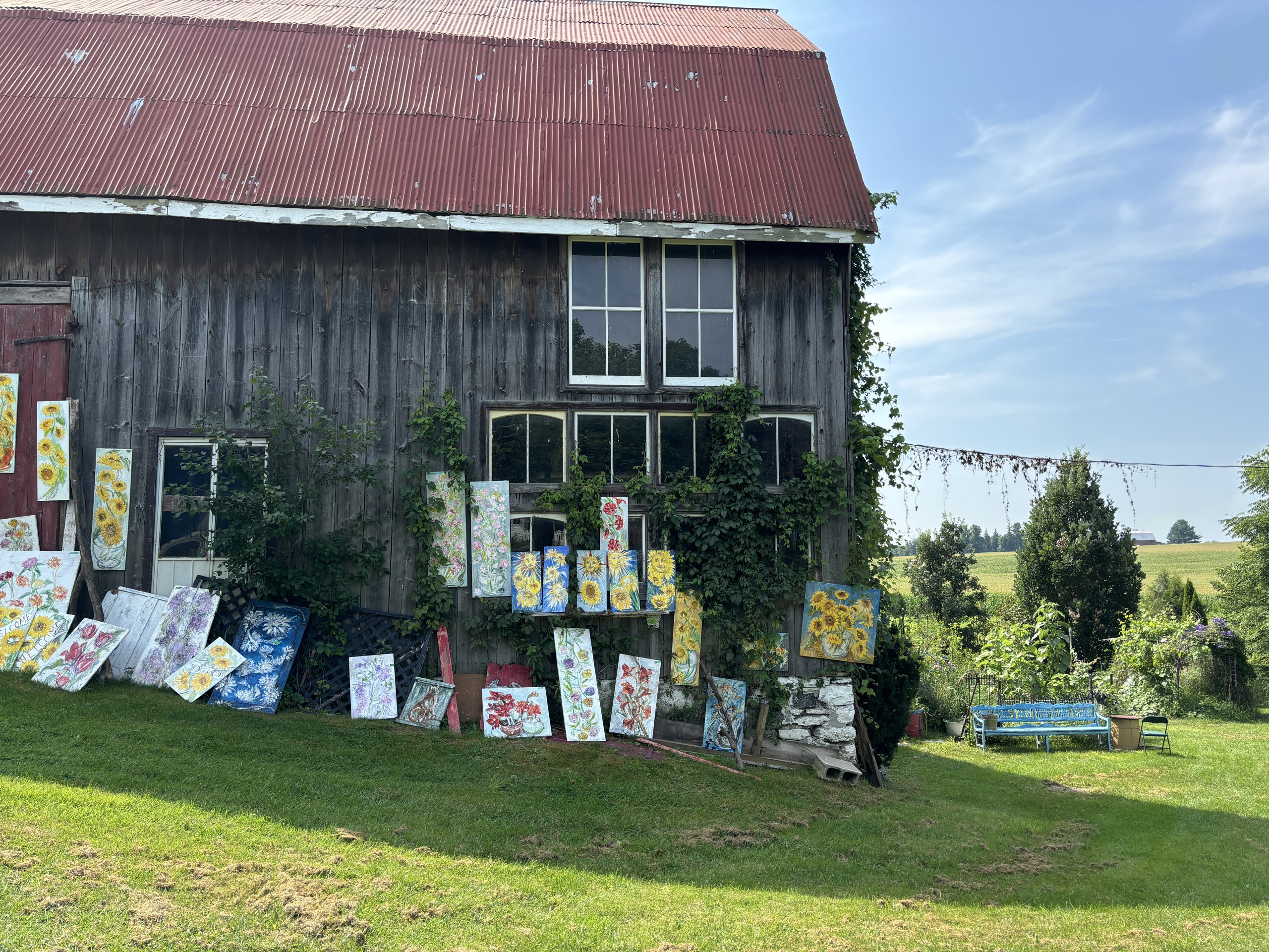 Photo of a barn with many paintings displayed out front,