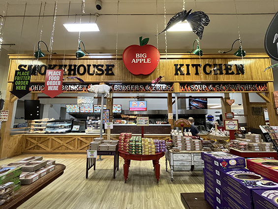 A large industrial kitchen with pies and other baked goods displayed on tables in front.