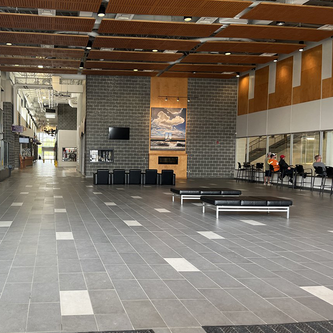 Large open space with grey brick walls and a brown roof and multiple seating areas.
