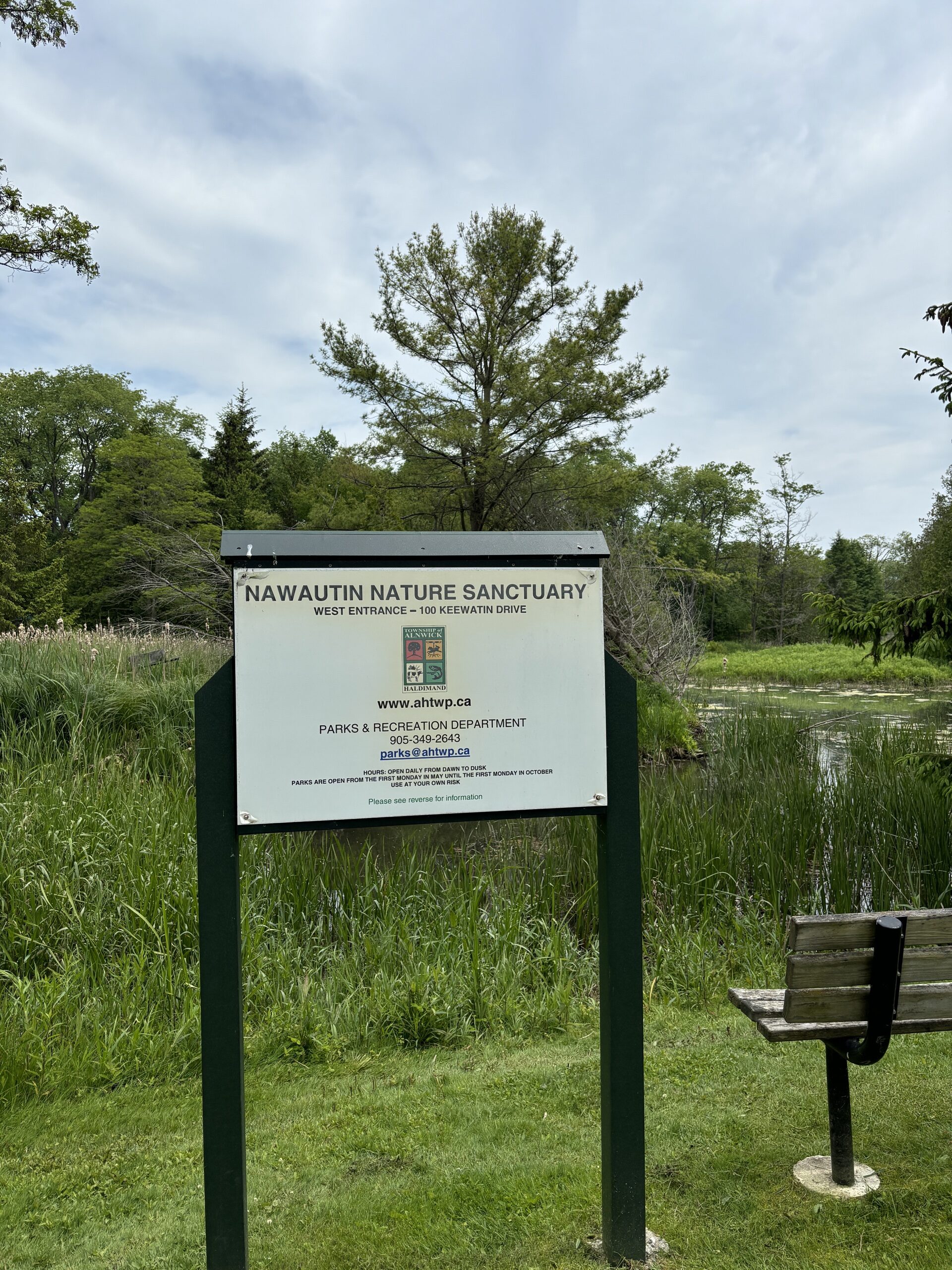 Photo of Nawautin Nature Sanctuary sign. Sign reads "Nawautin Nature Sanctuary. West Entrance - 100 Keewatin Drive. www.ahtwp.ca. Parks & Recreation Department 905-349-2643."