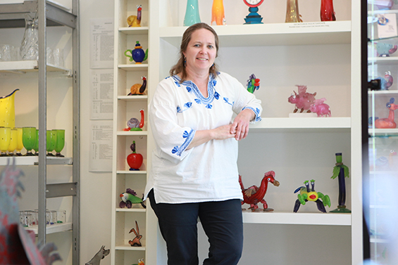 Woman leaning on shelf with unique creations.
