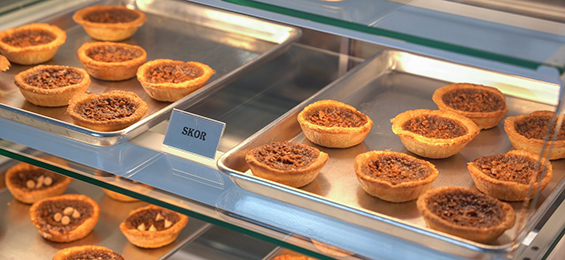 Trays of butter tarts in a glass case.
