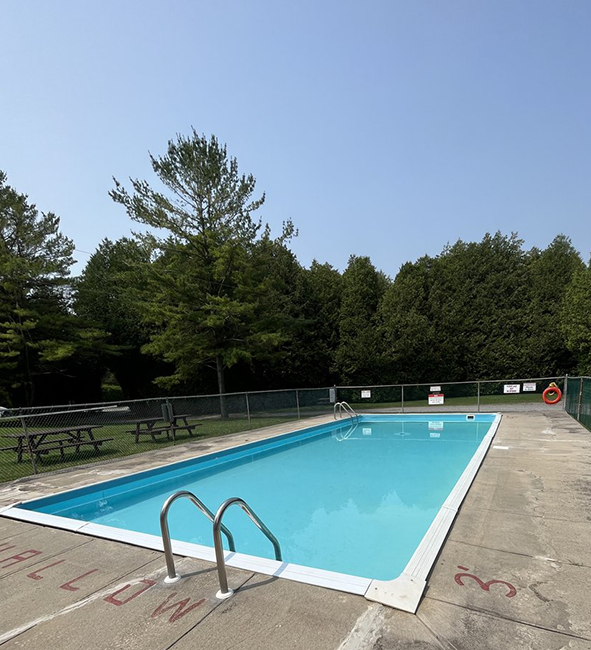 Rectangular in ground pool enclosed by a fence.